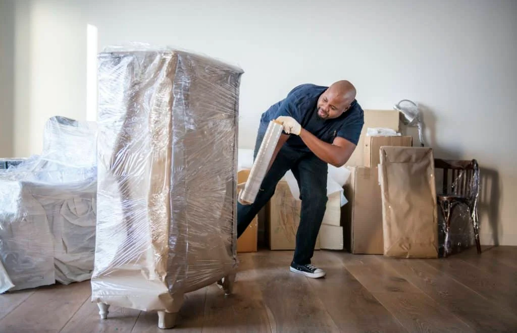 Team of professional movers wrapping and packing household items for safe transport in UAE.